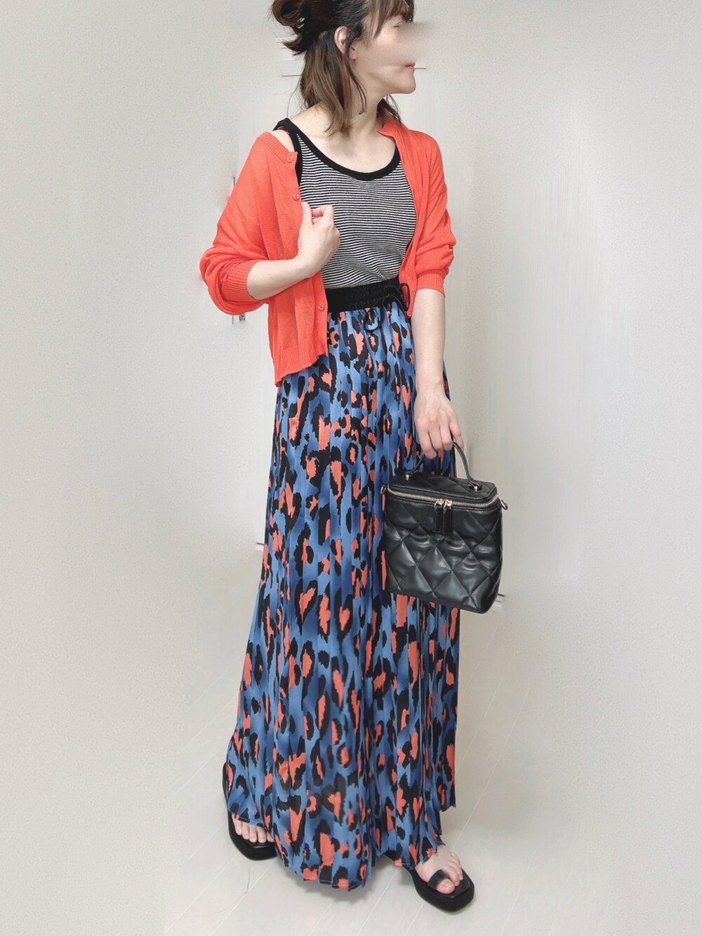 ブルー系のスカート、オレンジ系のカーディガン/ボレロ、ブラック系のタンクトップを着用したレディースの夏コーディネートの4枚目の写真