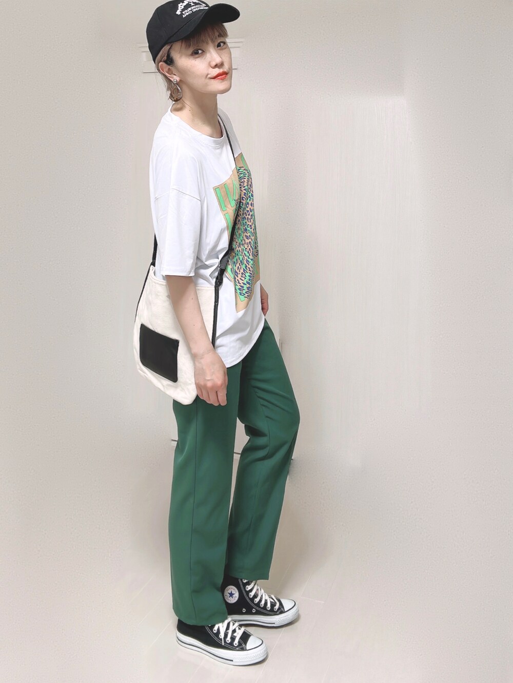 ホワイト系のショルダーバッグ、グリーン系のスラックス、ブラック系のスニーカーを着用したレディースの夏コーディネートの3枚目の写真