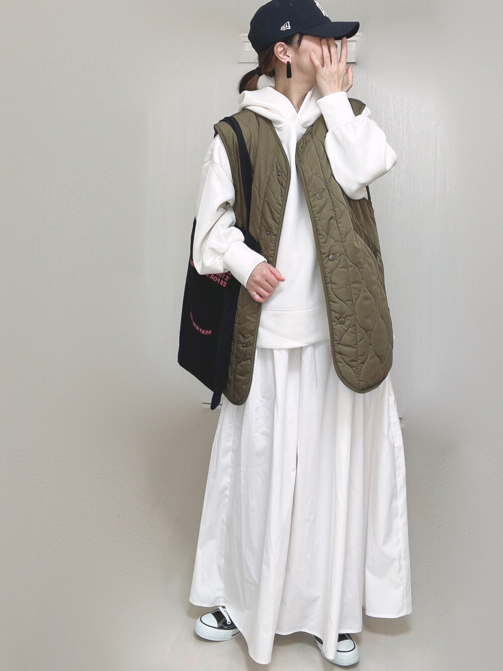 ホワイト系のパーカー、ブラック系のトートバッグ、ホワイト系のスカートを着用したレディースの秋コーディネートの2枚目の写真