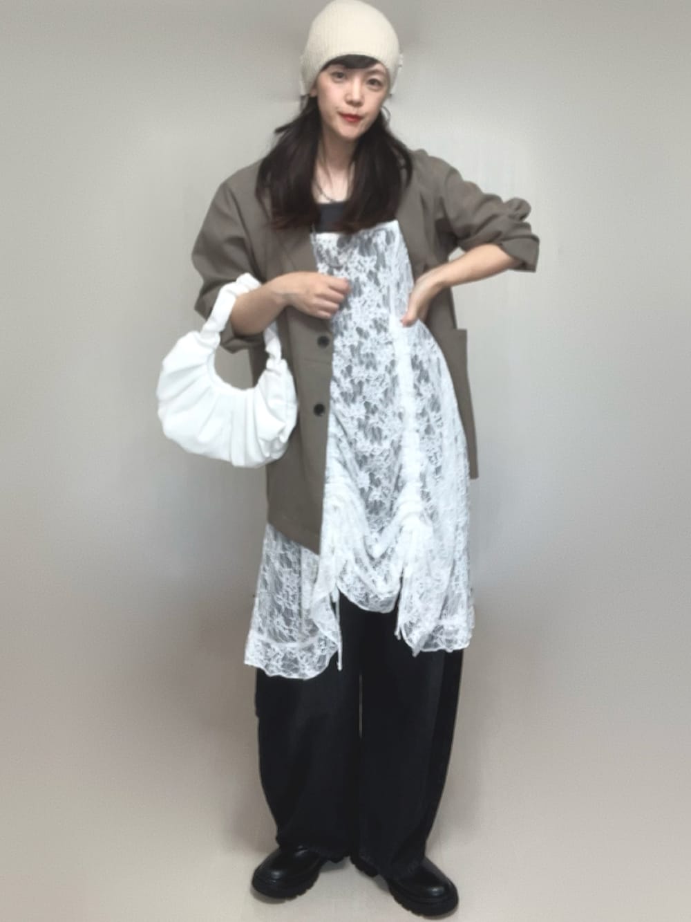 ベージュ系のテーラードジャケット、ホワイト系のチュニック、ブラック系のブーツを着用したレディースの夏コーディネートの5枚目の写真