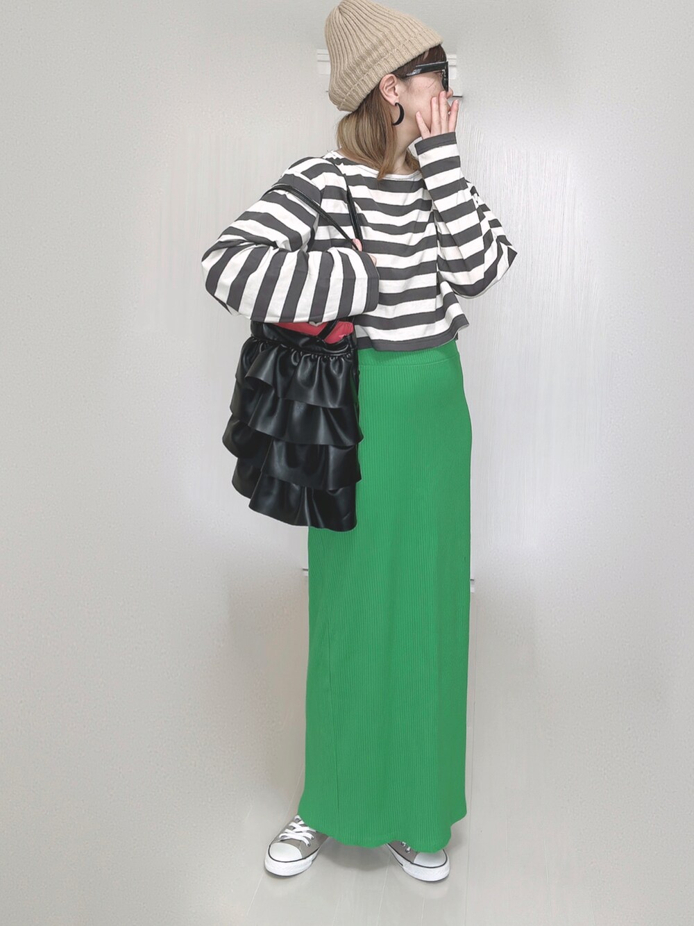 グリーン系のスカート、ベージュ系のニットキャップ/ビーニー、ブラック系のメガネを着用したレディースの秋コーディネートの5枚目の写真