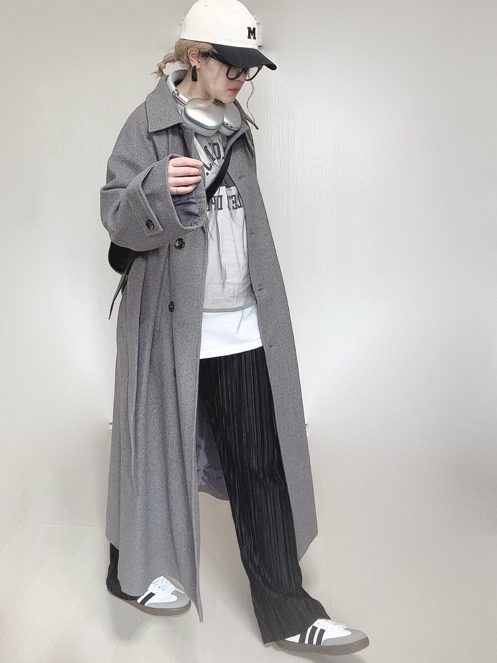 グレー系のステンカラーコート、ホワイト系のTシャツ/カットソー、ブラック系のその他パンツを着用したレディースの冬コーディネートの2枚目の写真