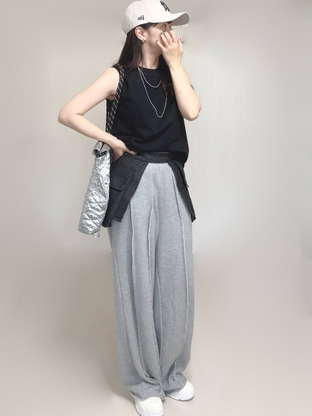 グレー系のスウェットパンツ、シルバー系のトートバッグ、ホワイト系のスニーカーを着用したレディースの夏コーディネートの2枚目の写真