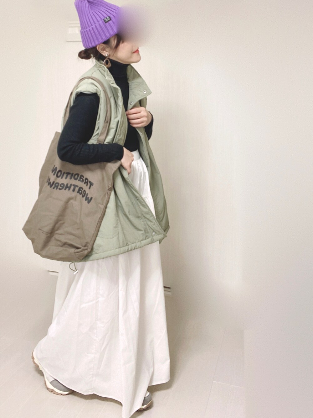 グリーン系のダウンジャケット/コート、ホワイト系のスカート、ベージュ系のスニーカーを着用したレディースの秋コーディネートの3枚目の写真