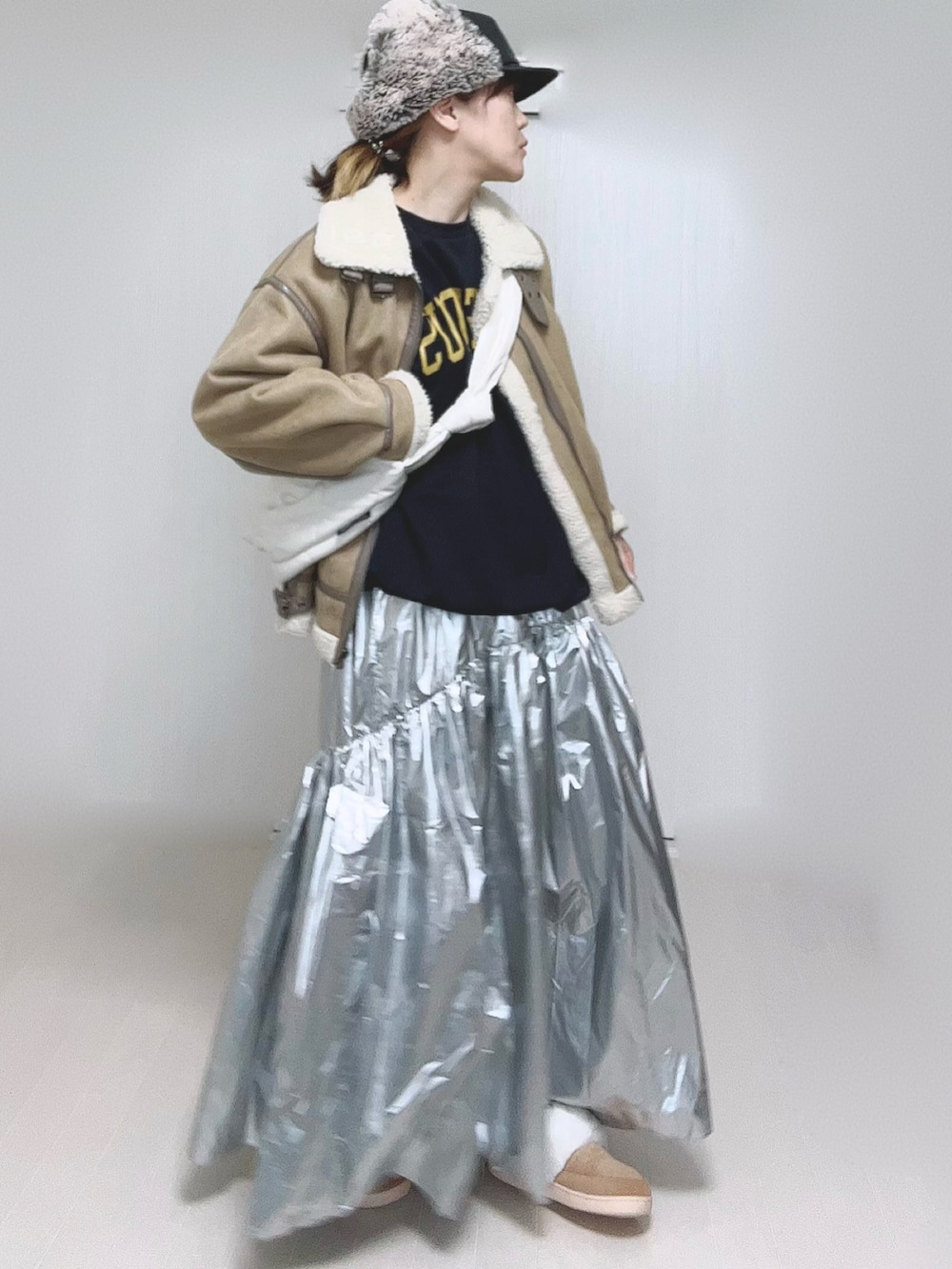 ベージュ系のムートンコート、ホワイト系のショルダーバッグ、シルバー系のスカートを着用したレディースの冬コーディネートの4枚目の写真