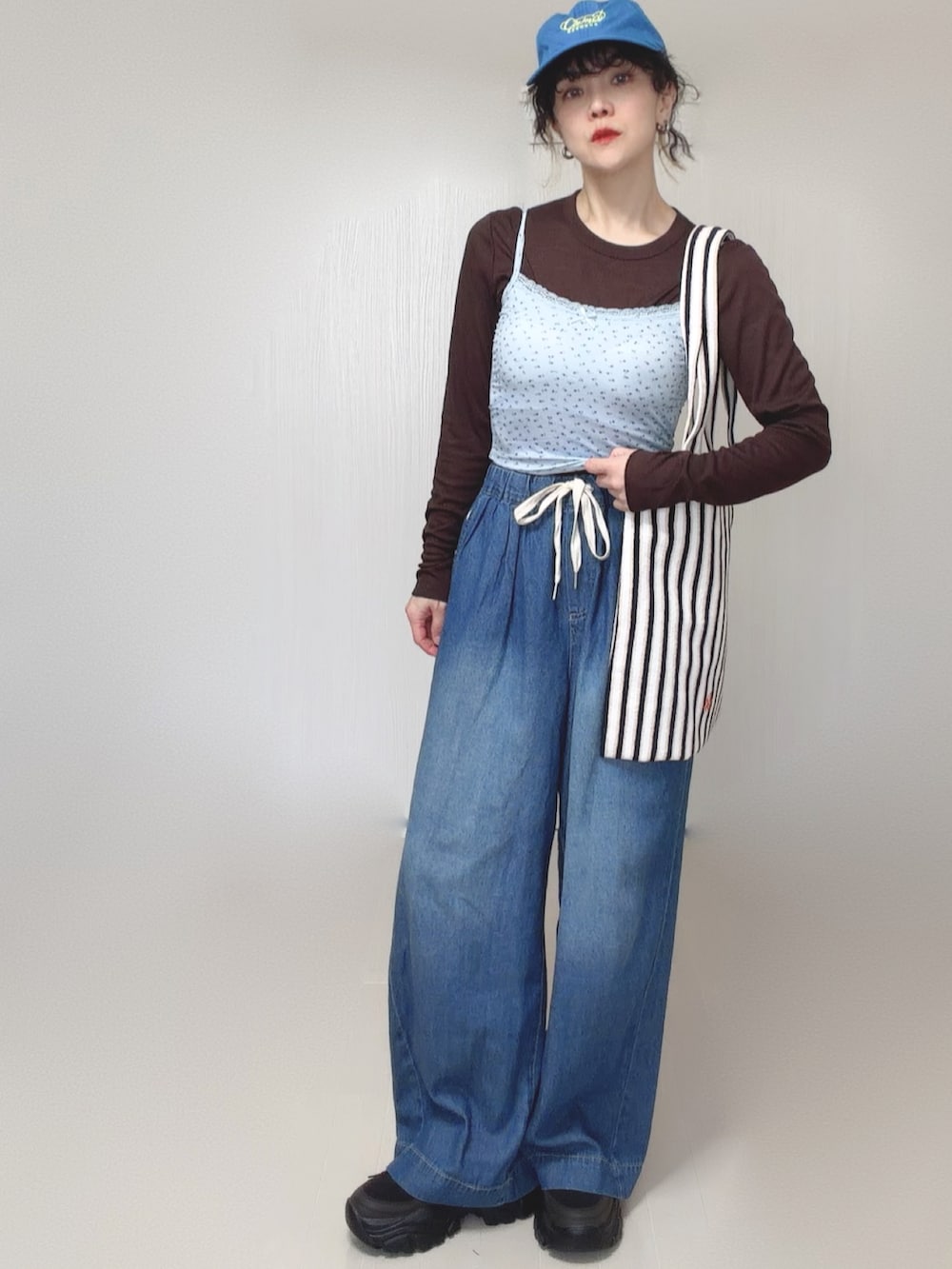ブルー系のキャミソール、ブルー系のデニムパンツ、ホワイト系のトートバッグを着用したレディースの春コーディネートの2枚目の写真