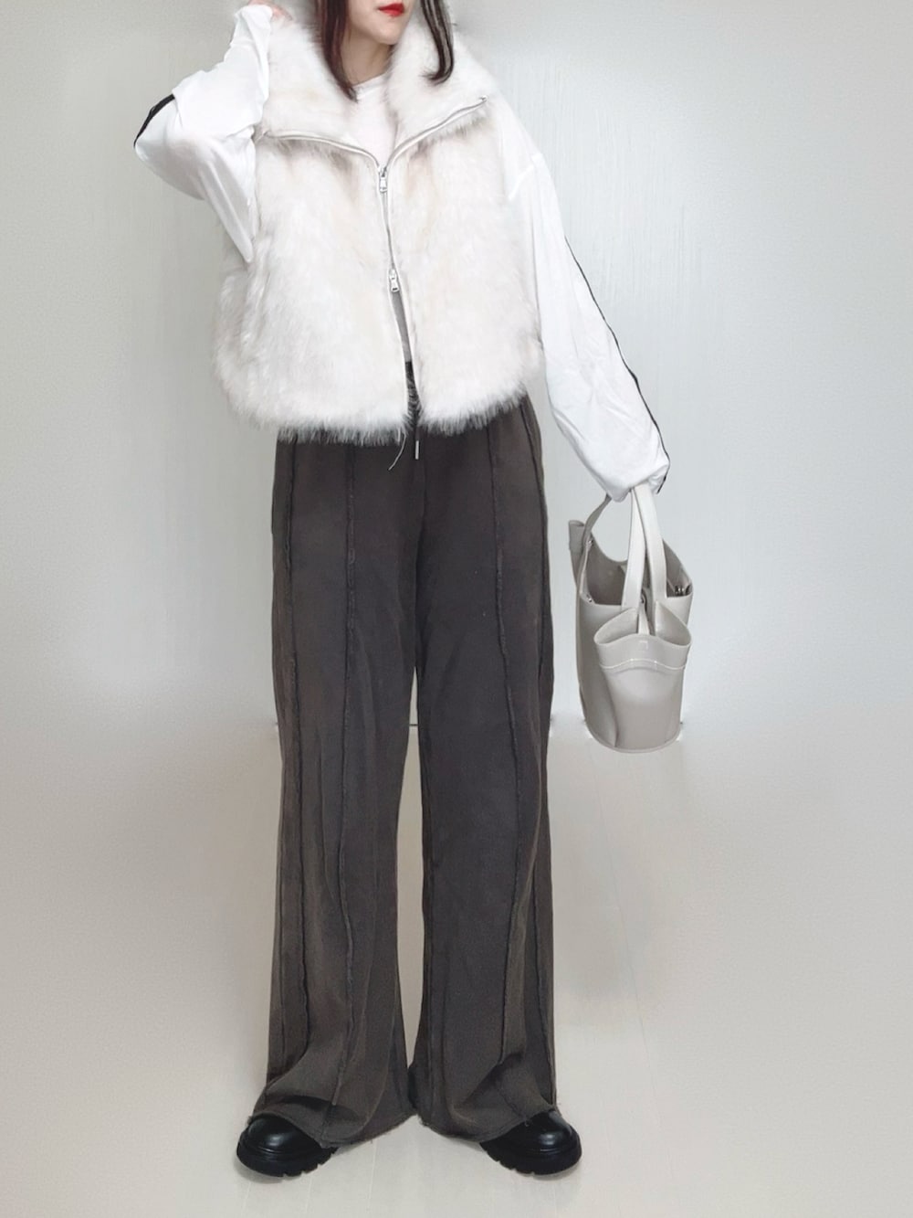 ホワイト系のベスト、ブラック系のブーツ、ホワイト系のTシャツ/カットソーを着用したレディースの秋コーディネートの4枚目の写真