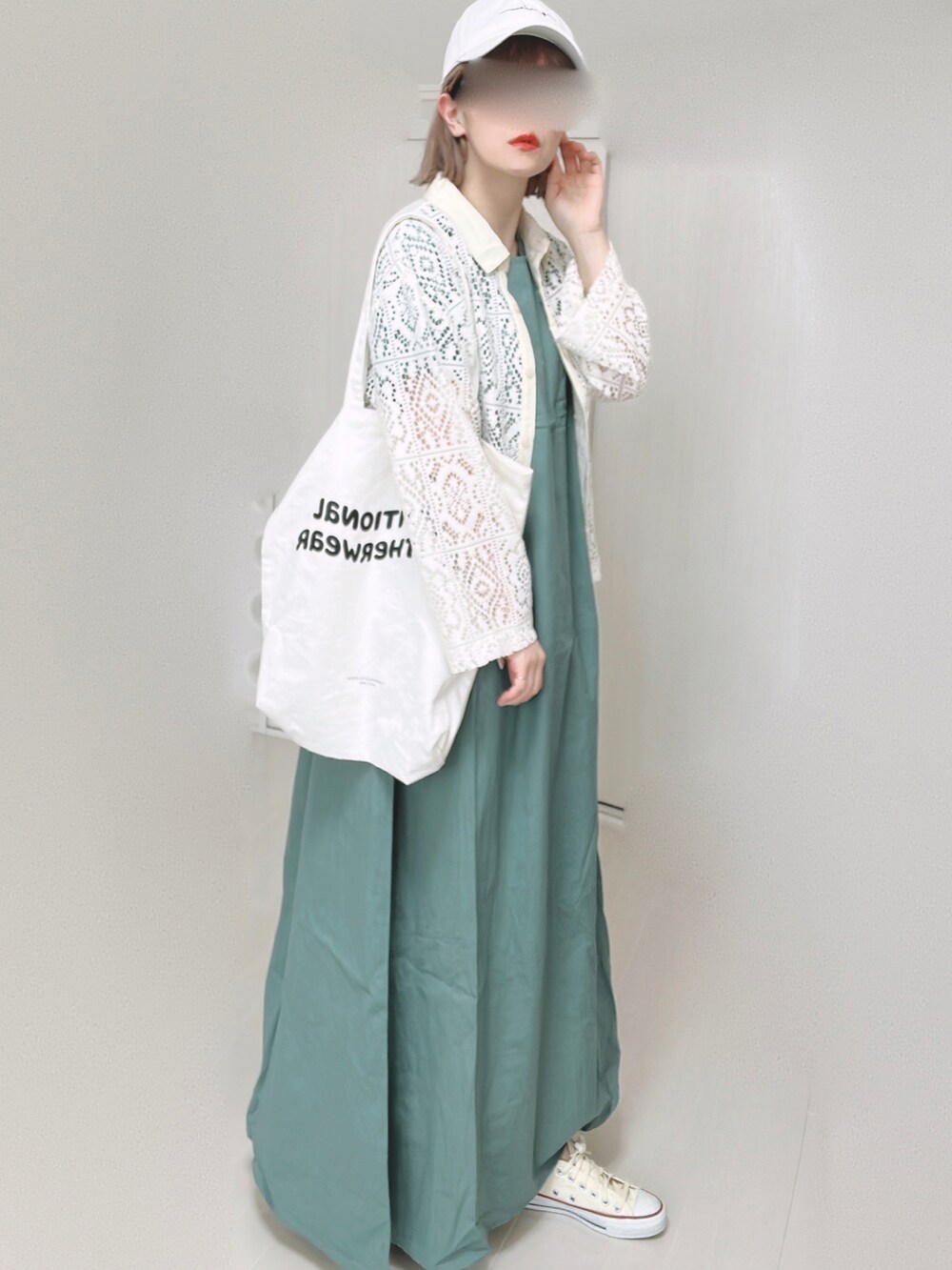 グリーン系のワンピース、ホワイト系のトートバッグ、ホワイト系のスニーカーを着用したレディースの春コーディネートの4枚目の写真