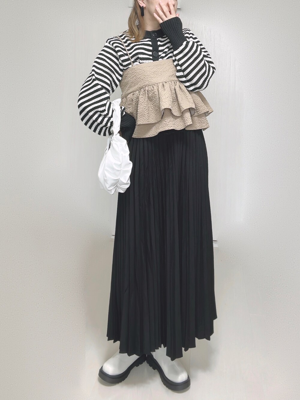 ホワイト系のカーディガン/ボレロ、ベージュ系のキャミソール、ブラック系のスカートを着用したレディースの秋コーディネートの5枚目の写真