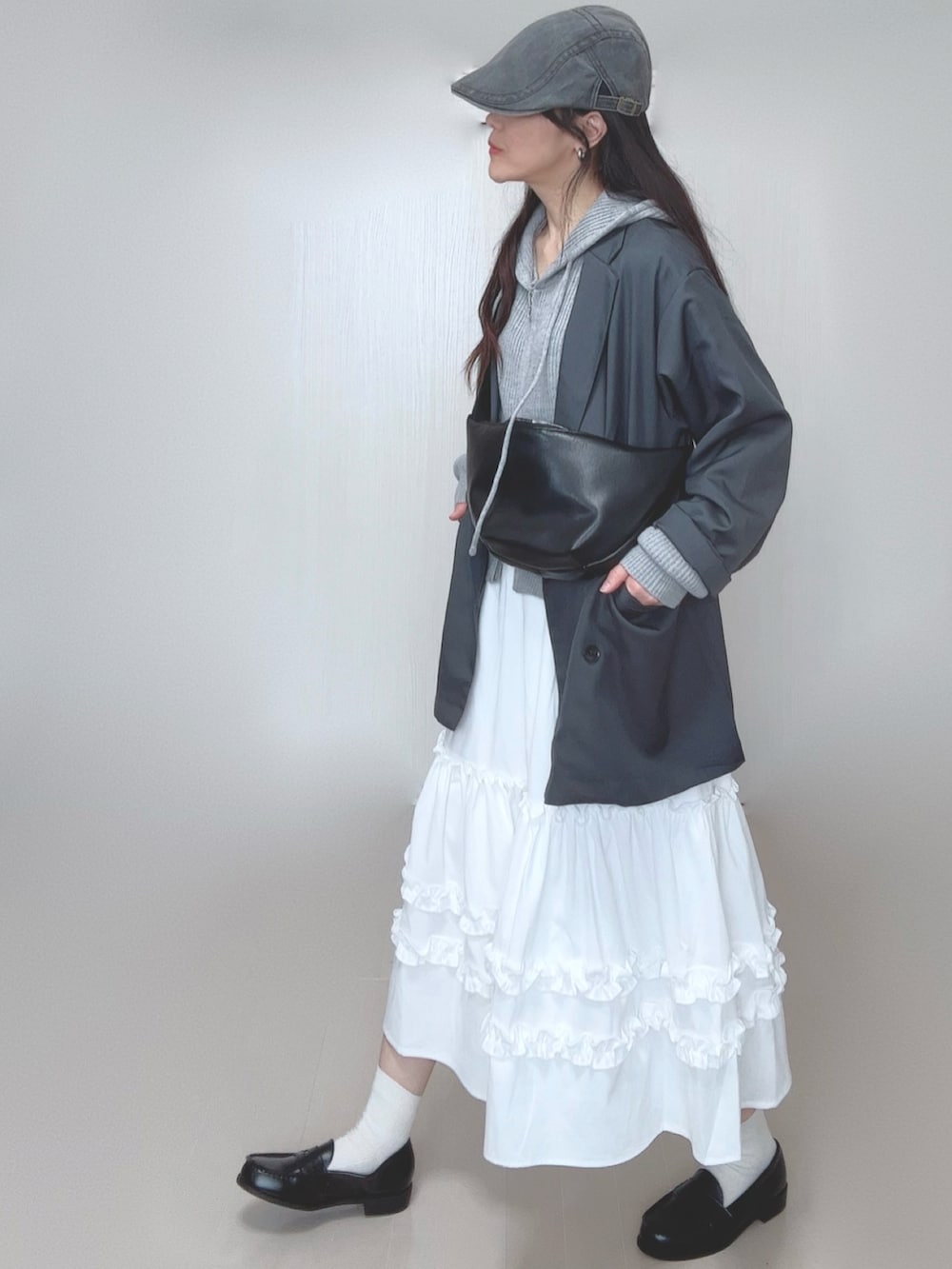 グレー系のパーカー、グレー系のテーラードジャケット、ホワイト系のスカートを着用したレディースの春コーディネートの2枚目の写真