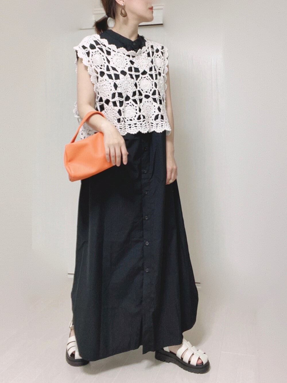 ブラック系のワンピース、オレンジ系のショルダーバッグを着用したレディースの夏コーディネートの3枚目の写真