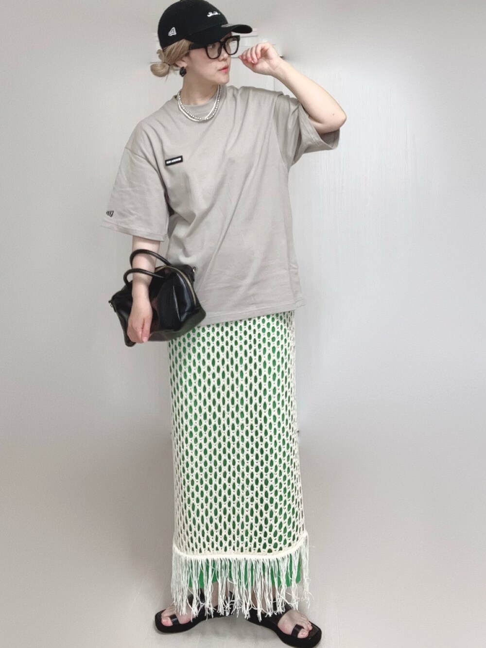 ホワイト系のスカート、ベージュ系のTシャツ/カットソー、ブラック系のサンダルを着用したレディースの夏コーディネートの2枚目の写真