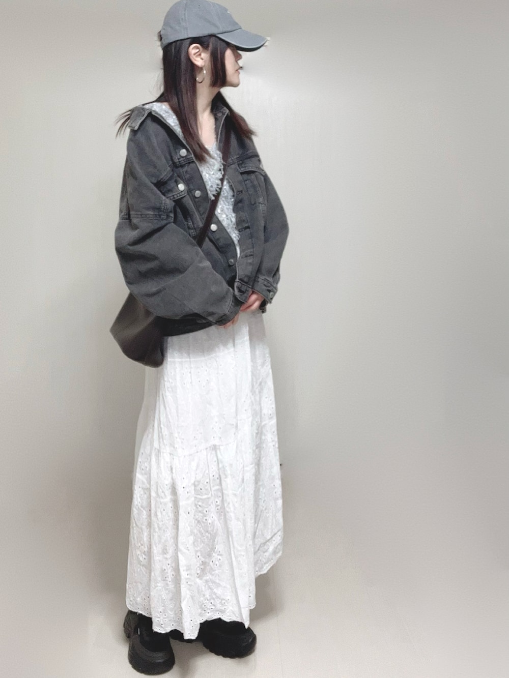 グレー系のベスト、ブラック系のデニムジャケット、ホワイト系のスカートを着用したレディースの春コーディネートの5枚目の写真