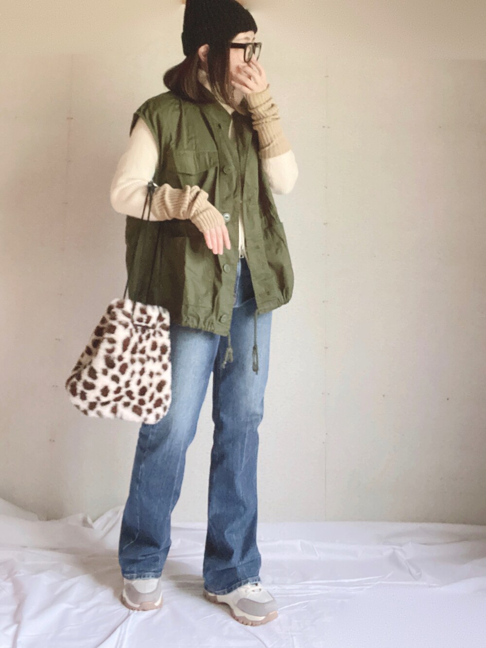 ブルー系のデニムパンツ、ベージュ系のスニーカー、ホワイト系のニット/セーターを着用したレディースの秋コーディネートの4枚目の写真