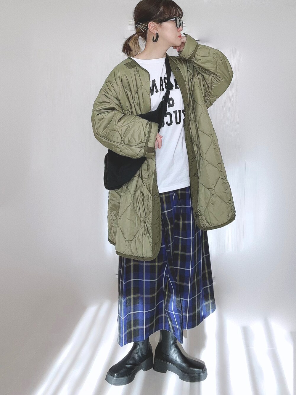 ホワイト系のTシャツ/カットソー、グリーン系のミリタリージャケット、ブラック系のブーツを着用したレディースの冬コーディネートの3枚目の写真