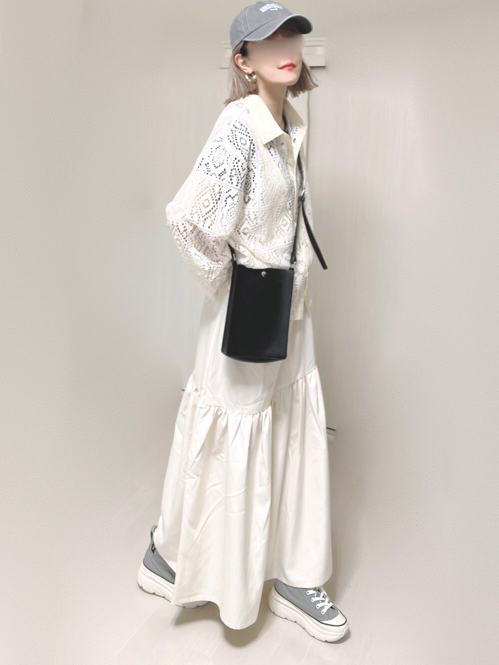 ホワイト系のジャンパースカート、ブラック系のショルダーバッグ、グレー系のスニーカーを着用したレディースの春コーディネートの3枚目の写真