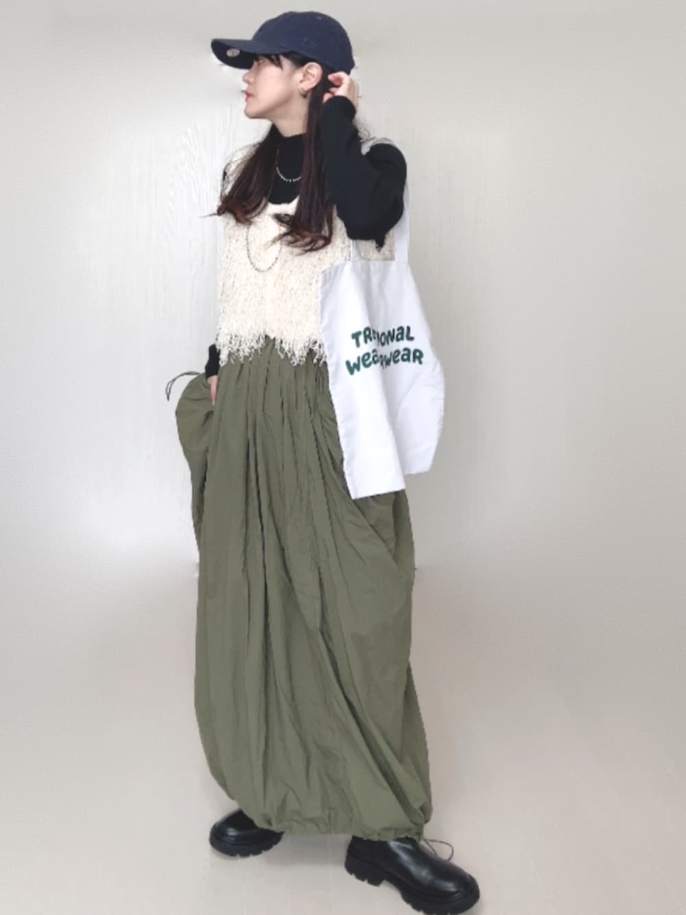 ホワイト系のベスト、ブラック系のニット/セーター、グリーン系のスカートを着用したレディースの秋コーディネートの5枚目の写真