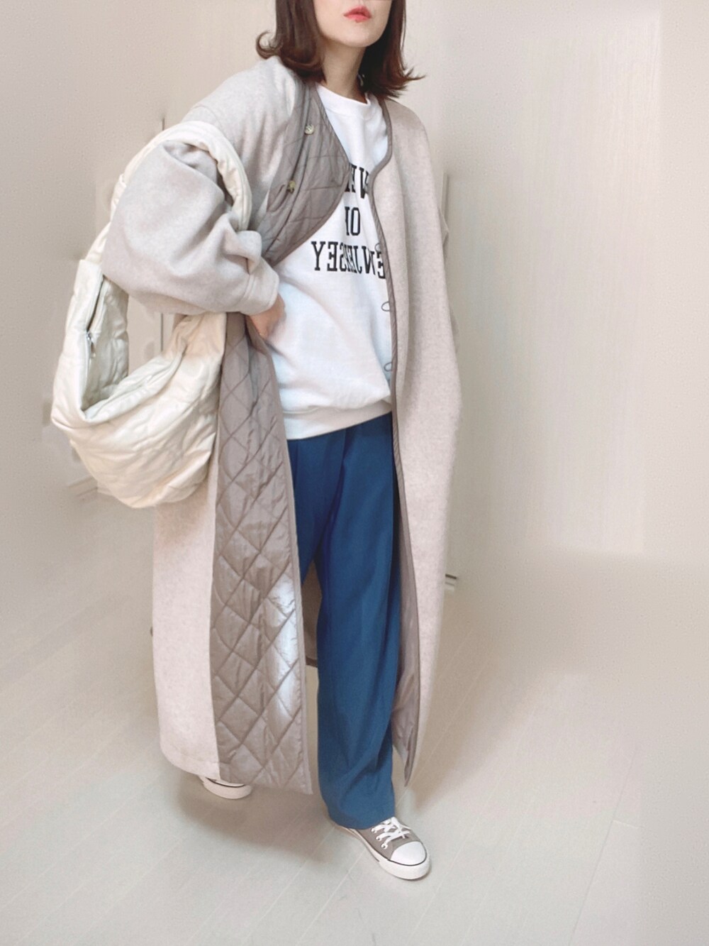 ベージュ系のノーカラーコート、ホワイト系のスウェット、ブルー系のその他パンツを着用したレディースの冬コーディネートの4枚目の写真