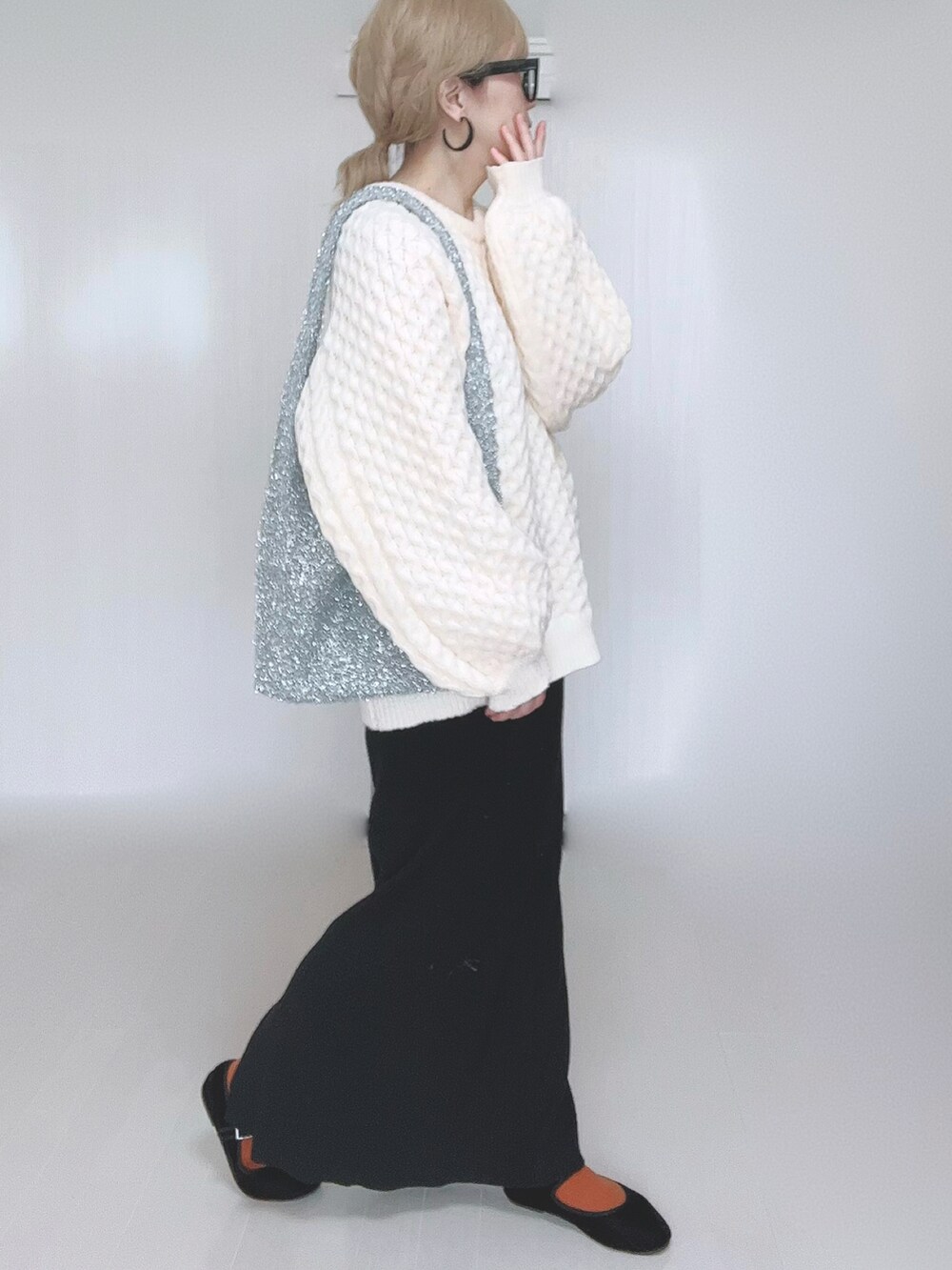 ホワイト系のニット/セーター、ブラック系のスカート、ブラック系のパンプスを着用したレディースの冬コーディネートの5枚目の写真