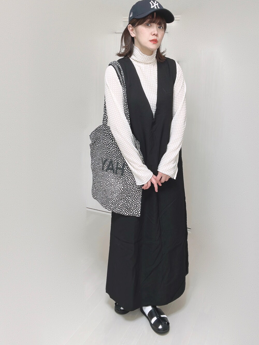 ホワイト系のTシャツ/カットソー、ブラック系のワンピース、ブラック系のサンダルを着用したレディースの春コーディネートの2枚目の写真