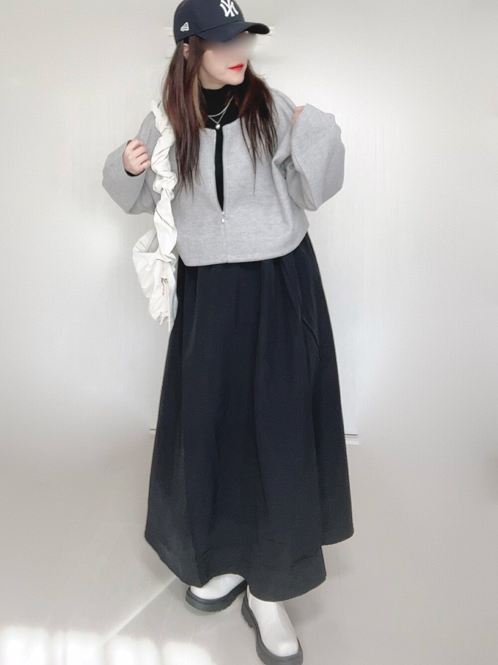 グレー系のワンピース、ホワイト系のショルダーバッグ、ホワイト系のブーツを着用したレディースの秋コーディネートの4枚目の写真