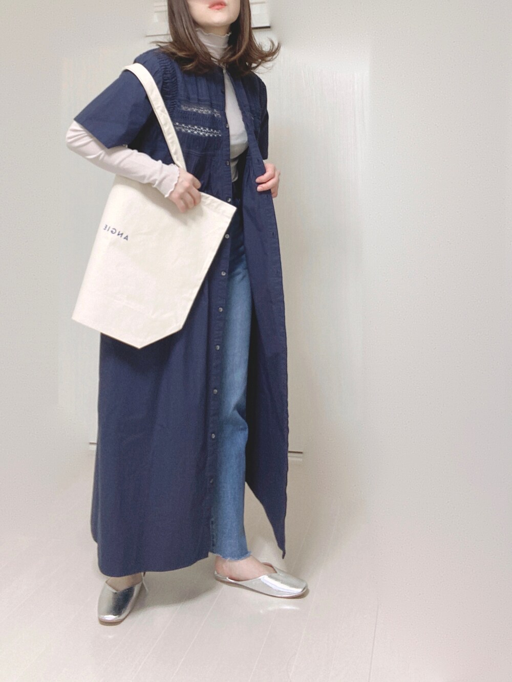 ホワイト系のトートバッグ、ブルー系のデニムパンツ、シルバー系のパンプスを着用したレディースの夏コーディネートの2枚目の写真