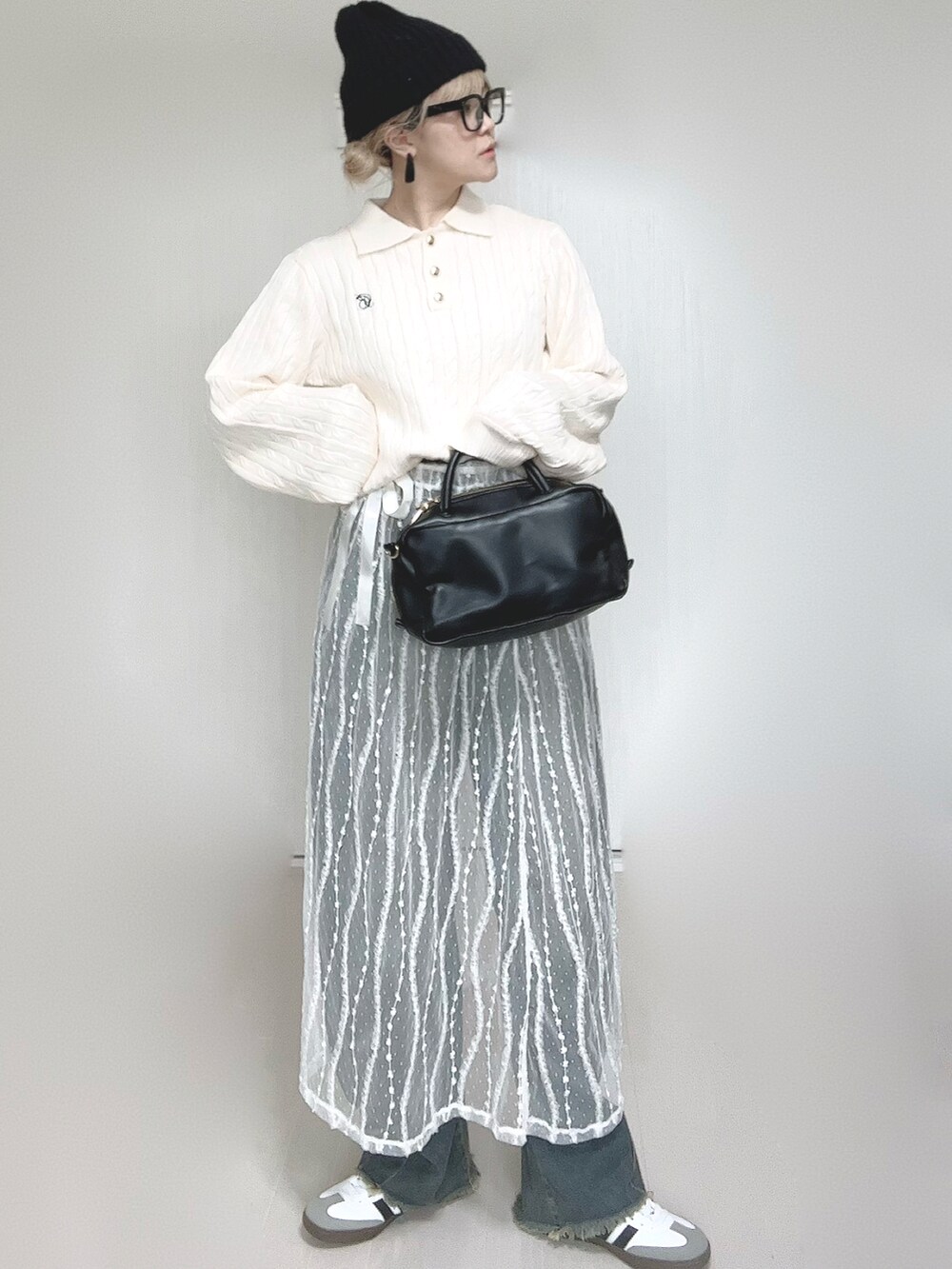 ホワイト系のニット/セーター、ブルー系のデニムパンツ、ホワイト系のスカートを着用したレディースの冬コーディネートの4枚目の写真