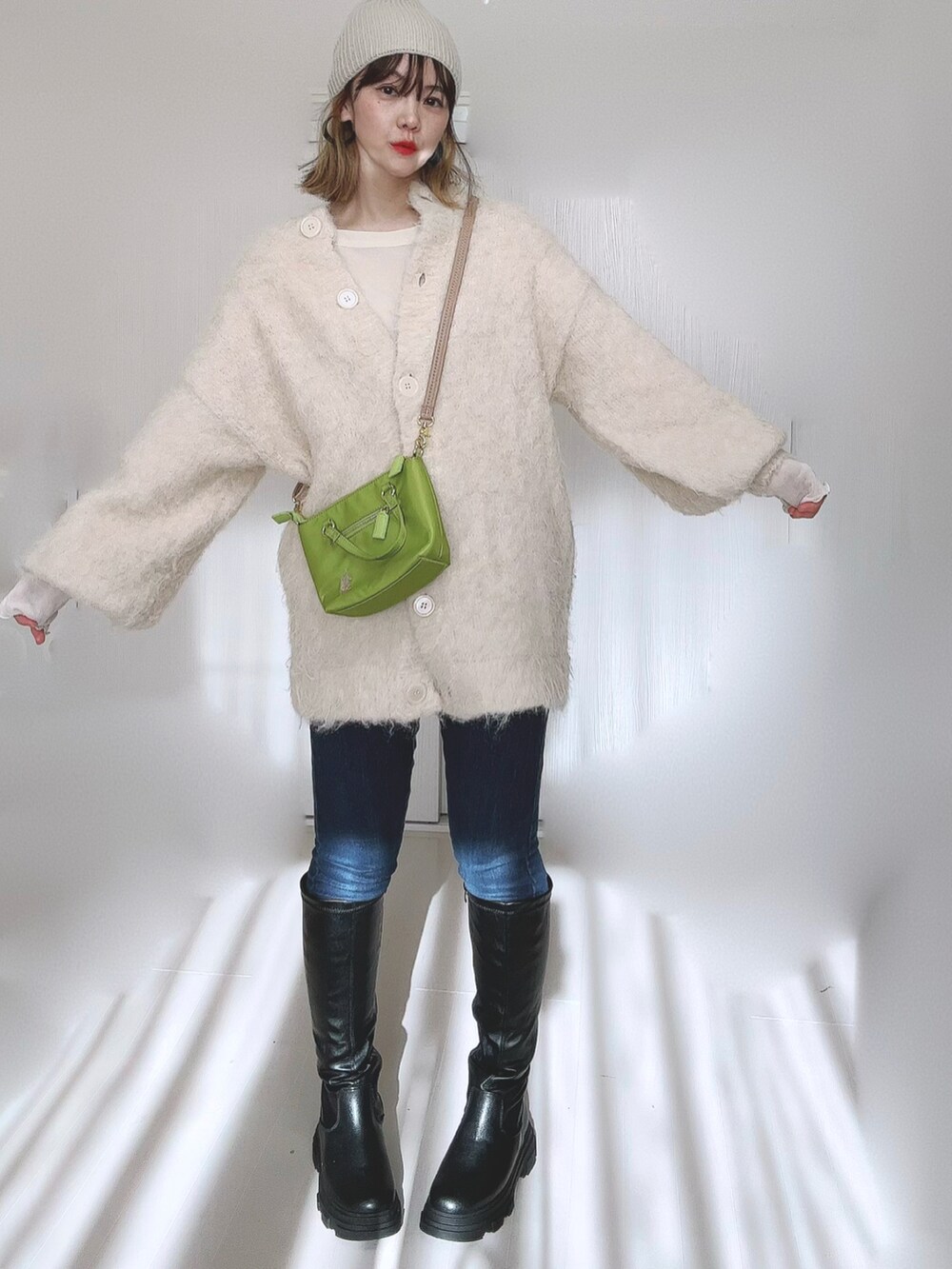 ブラック系のブーツ、ホワイト系のTシャツ/カットソー、ベージュ系のカーディガン/ボレロを着用したレディースの冬コーディネートの2枚目の写真