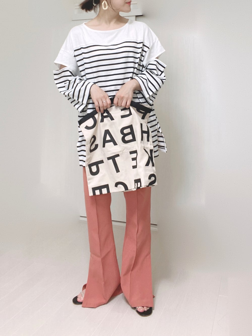 ピンク系のスラックス、ブラック系のTシャツ/カットソー、ホワイト系のトートバッグを着用したレディースの夏コーディネートの5枚目の写真