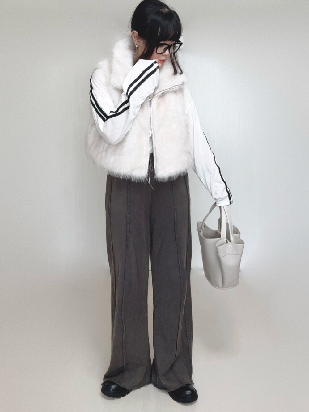 ホワイト系のベスト、ブラック系のブーツ、ホワイト系のTシャツ/カットソーを着用したレディースの秋コーディネートの2枚目の写真