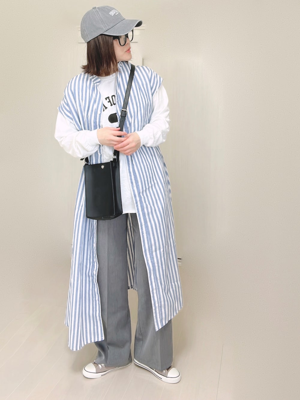 ブルー系のシャツワンピース、ホワイト系のTシャツ/カットソー、ブラック系のショルダーバッグを着用したレディースの春コーディネートの3枚目の写真