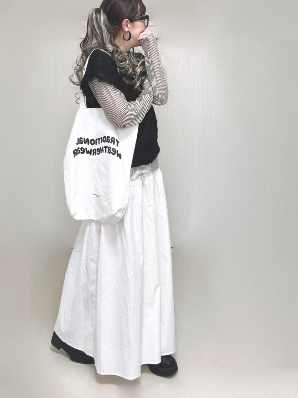 ブラック系のベスト、ホワイト系のシャツ/ブラウス、ホワイト系のトートバッグを着用したレディースの秋コーディネートの3枚目の写真