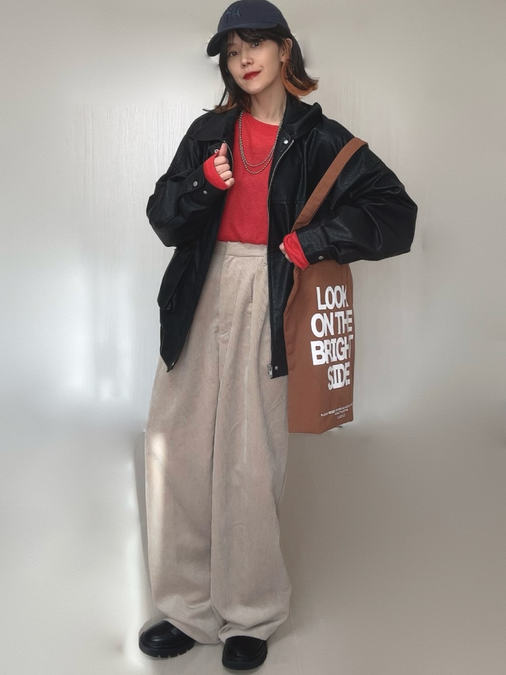 ブラック系のブルゾン、レッド系のTシャツ/カットソー、ブラック系のブーツを着用したレディースの冬コーディネートの4枚目の写真