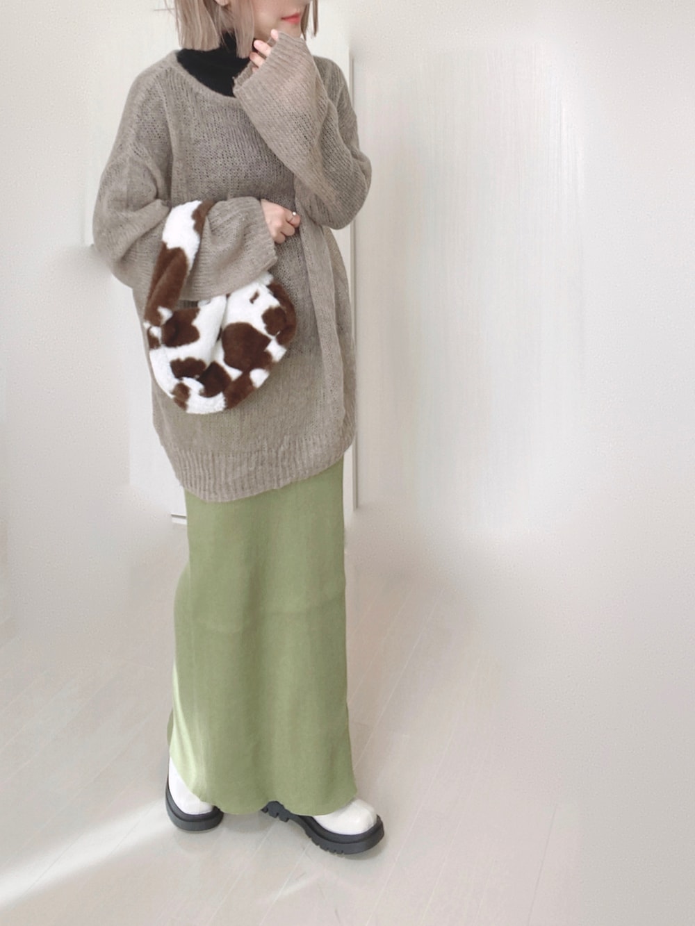 グリーン系のスカート、ベージュ系のニット/セーター、ホワイト系のブーツを着用したレディースの秋コーディネートの2枚目の写真