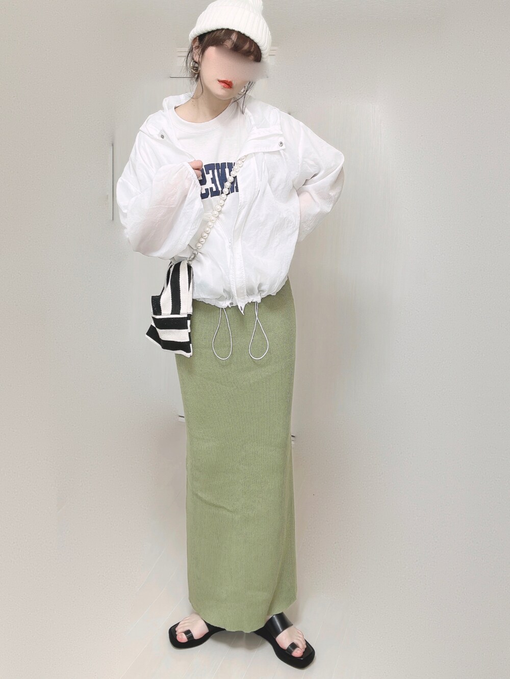 グリーン系のスカート、ホワイト系のショルダーバッグ、ブラック系のサンダルを着用したレディースの春コーディネートの2枚目の写真