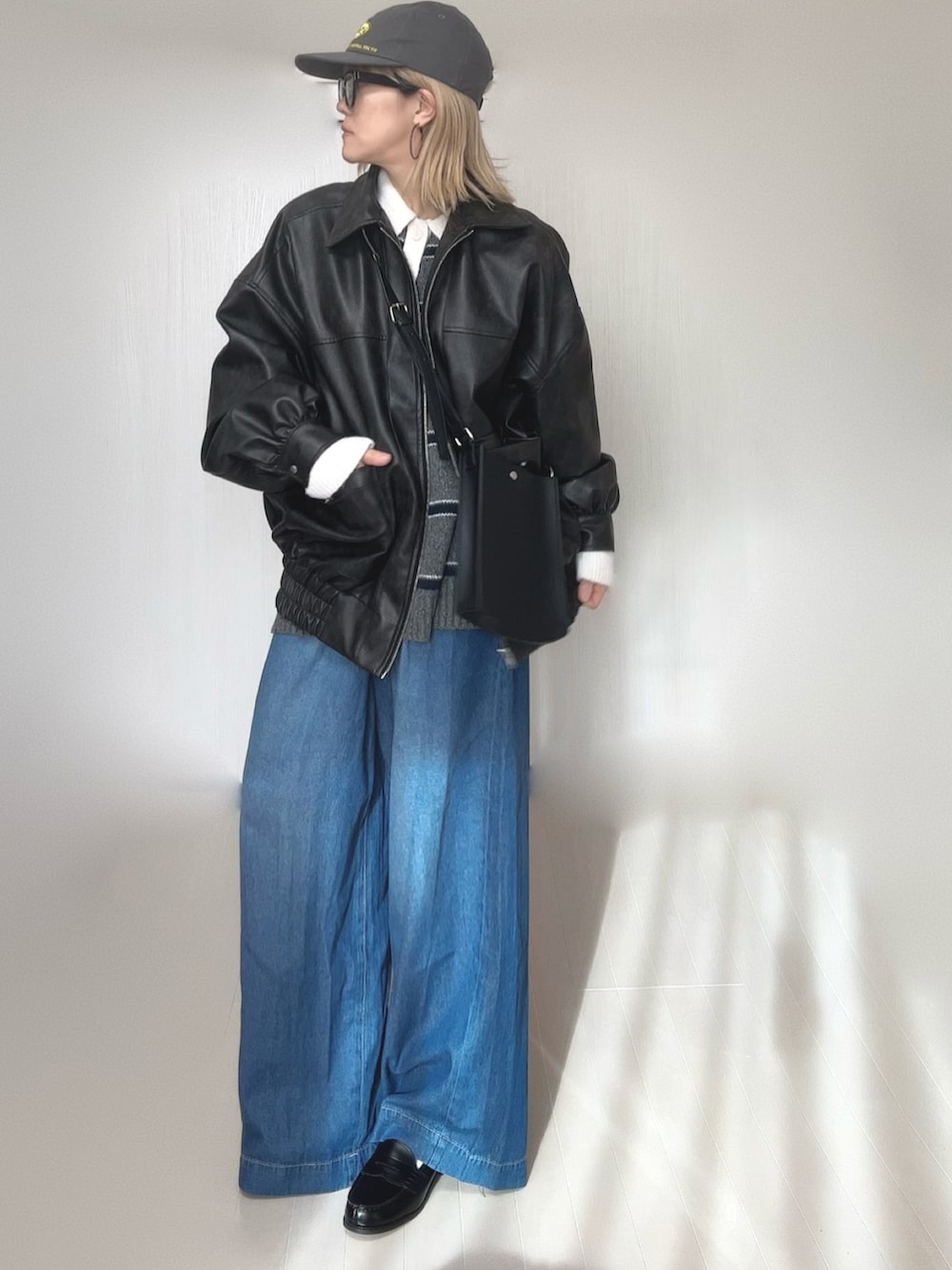 グレー系のニット/セーター、ブラック系のブルゾン、ブルー系のデニムパンツを着用したレディースの冬コーディネートの2枚目の写真