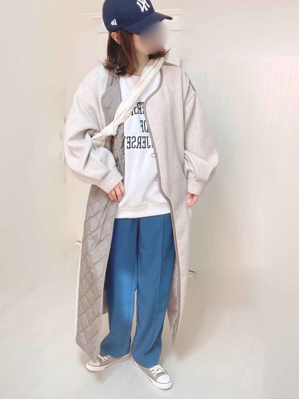 ベージュ系のノーカラーコート、ホワイト系のスウェット、ブルー系のその他パンツを着用したレディースの冬コーディネートの2枚目の写真