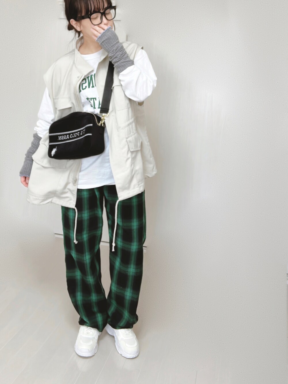 ホワイト系のTシャツ/カットソー、ホワイト系のベスト、ブラック系のショルダーバッグを着用したレディースの春コーディネートの2枚目の写真