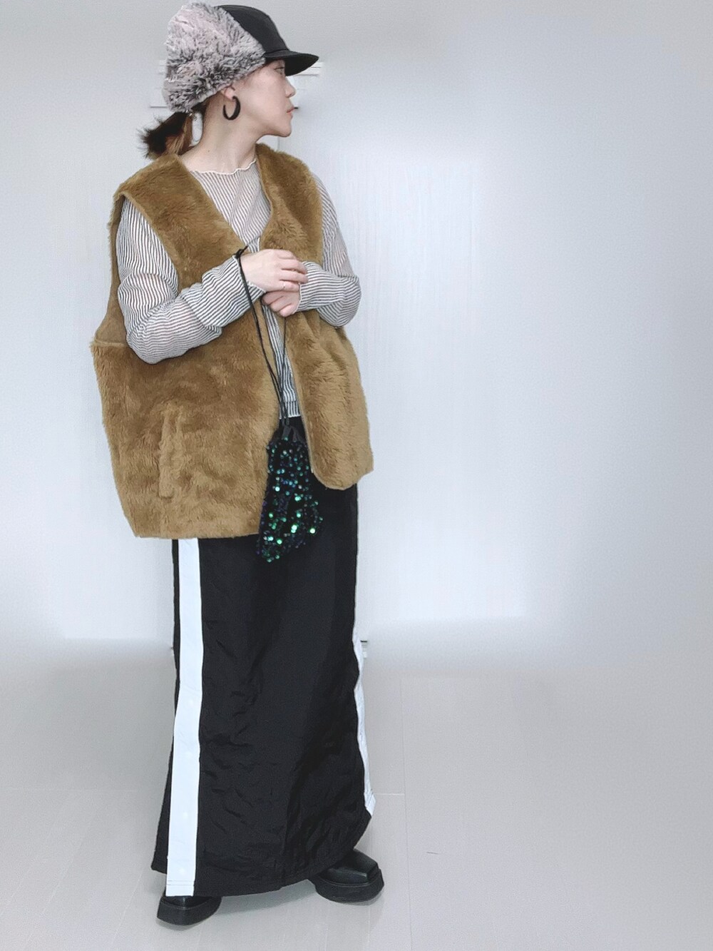 イエロー系のベスト、ホワイト系のシャツ/ブラウス、ブラック系のスカートを着用したレディースの冬コーディネートの5枚目の写真