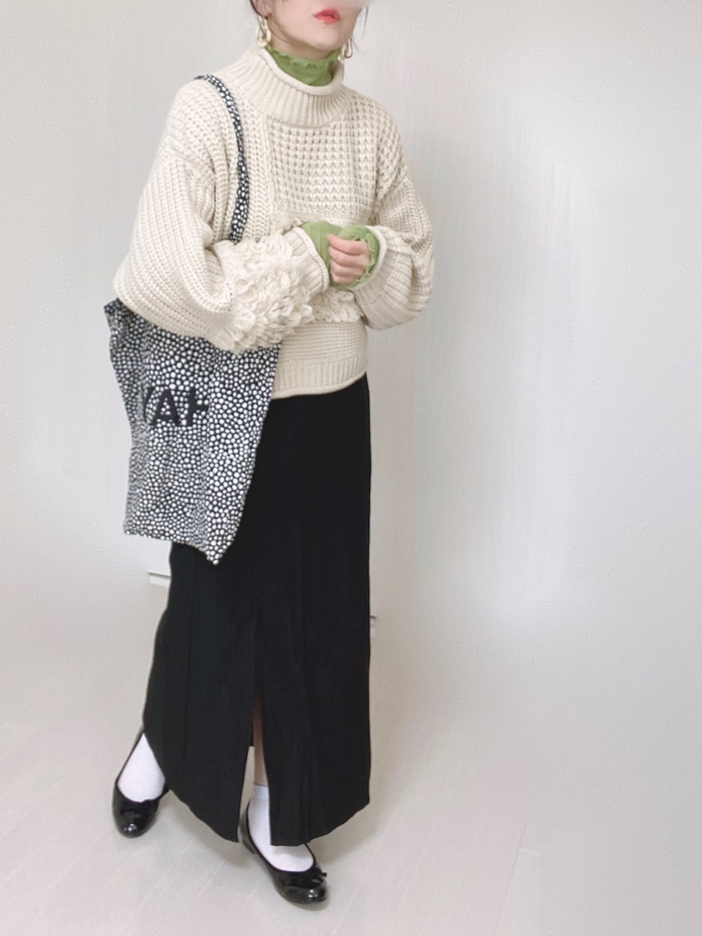 ホワイト系のニット/セーター、ブラック系のスカート、グリーン系のTシャツ/カットソーを着用したレディースの秋コーディネートの2枚目の写真