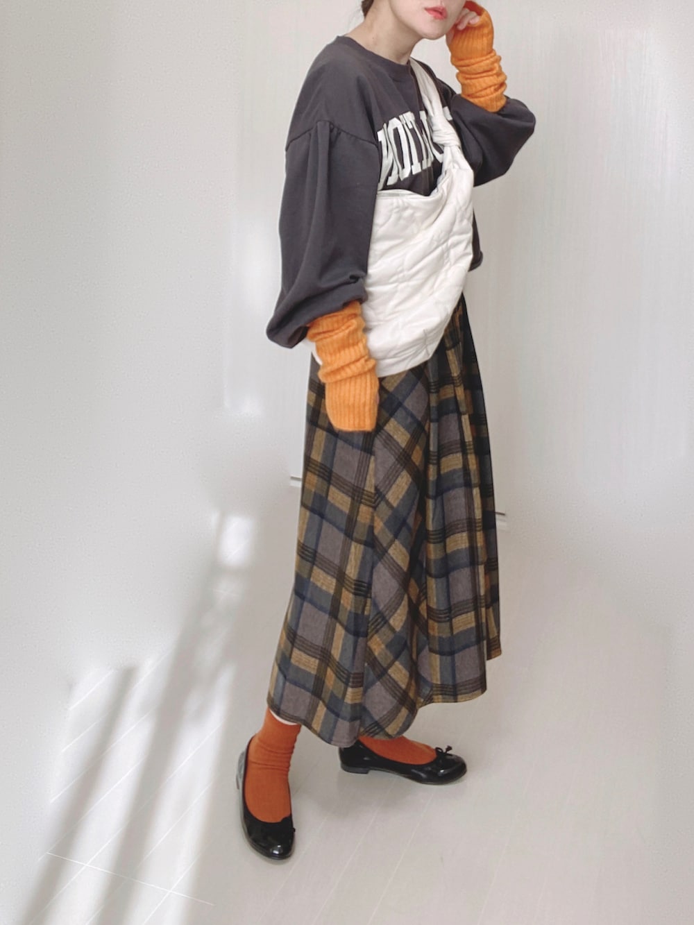 ホワイト系のショルダーバッグ、イエロー系のスカート、ブラック系のバレエシューズを着用したレディースの冬コーディネートの5枚目の写真