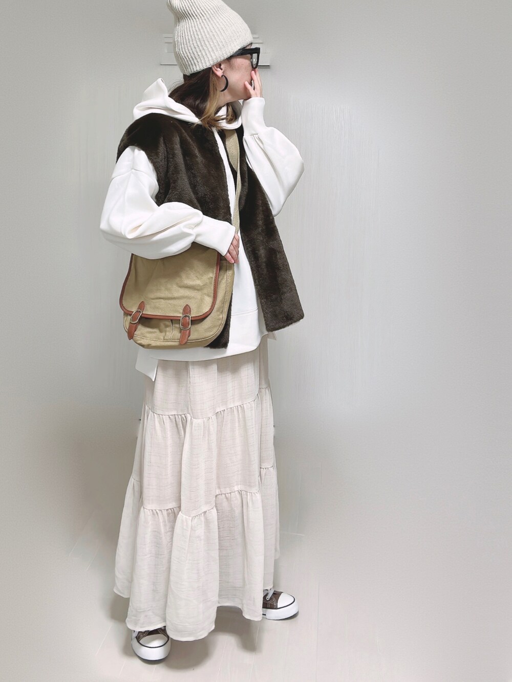 ブラウン系のベスト、ホワイト系のパーカー、ベージュ系のショルダーバッグを着用したレディースの秋コーディネートの5枚目の写真