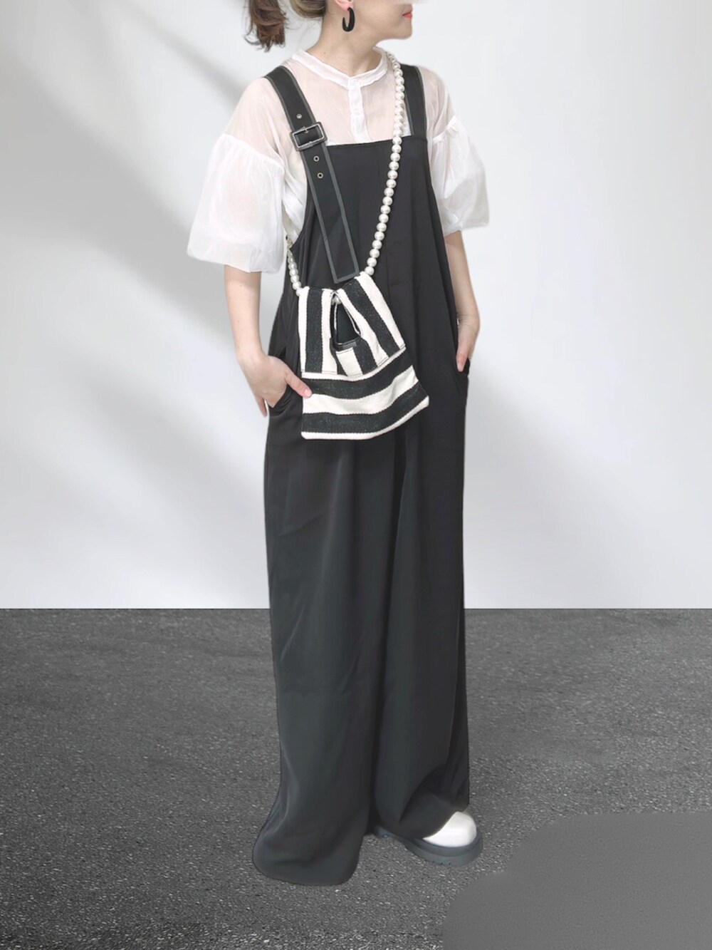 ブラック系のサロペット/オーバーオール、ホワイト系のシャツ/ブラウス、ホワイト系のショルダーバッグを着用したレディースの秋コーディネートの3枚目の写真