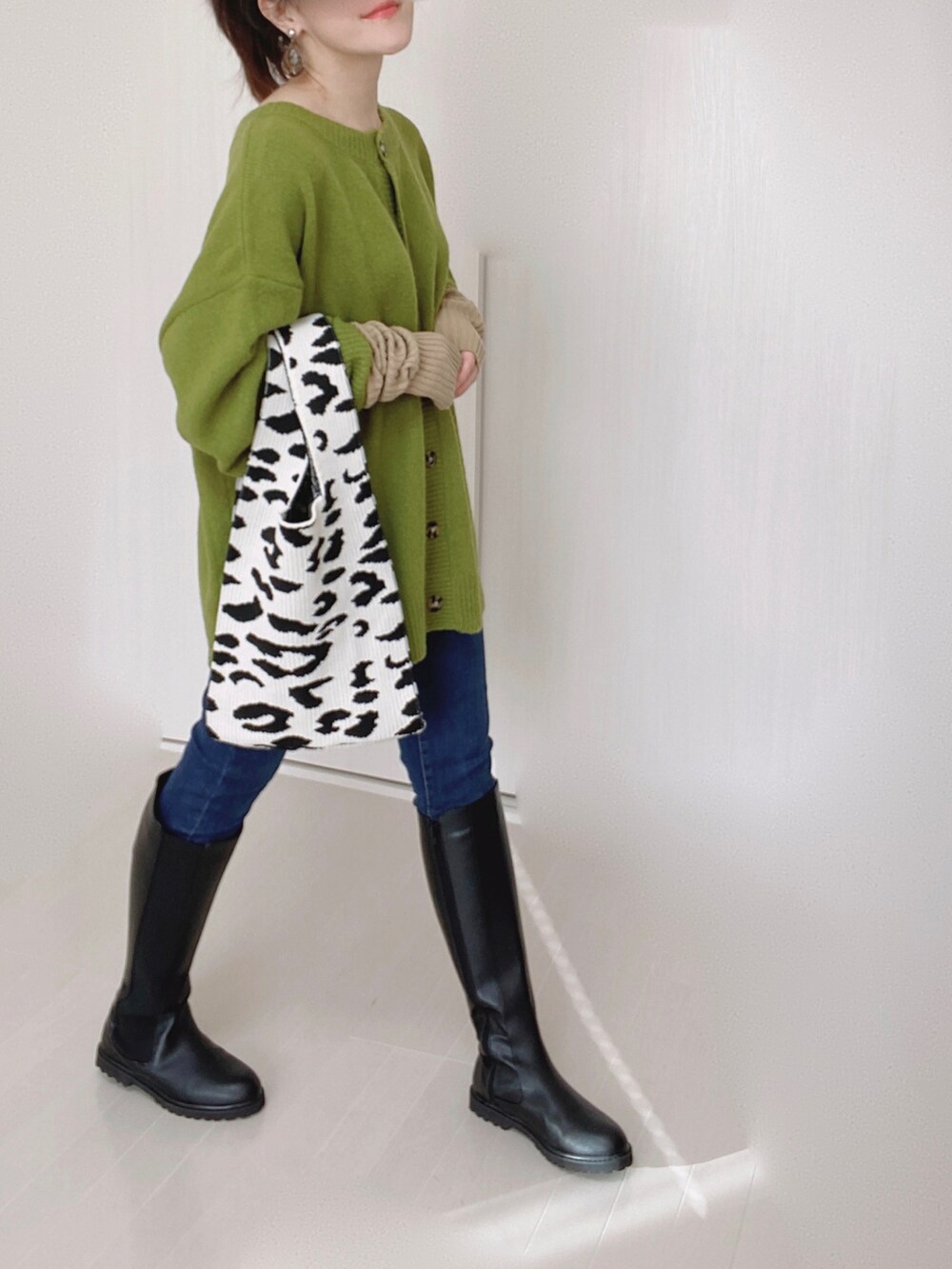 グリーン系のカーディガン/ボレロ、ブルー系のデニムパンツ、ブラック系のブーツを着用したレディースの秋コーディネートの4枚目の写真