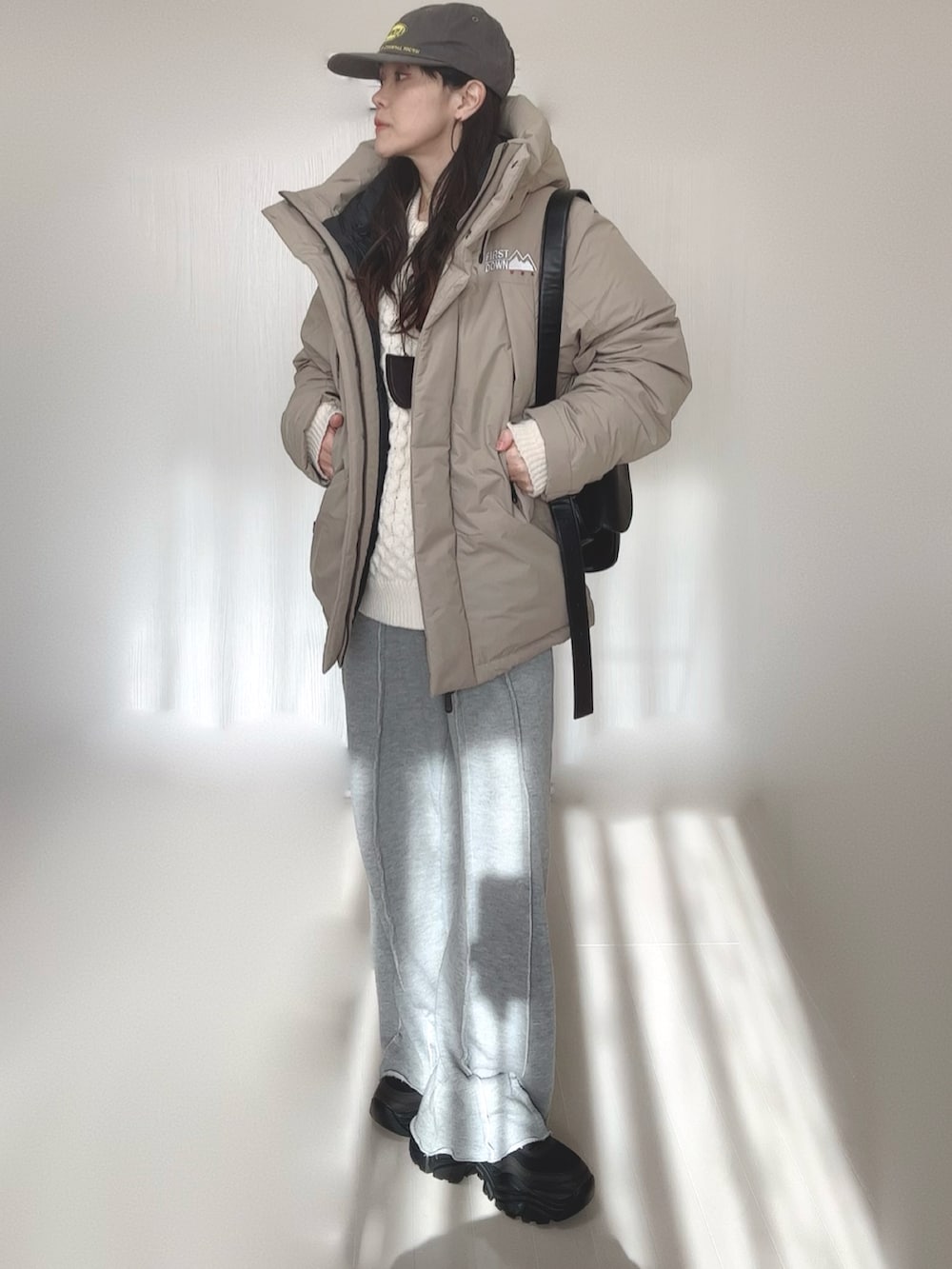 ベージュ系のダウンジャケット/コート、グレー系のスウェットパンツ、ホワイト系のニット/セーターを着用したレディースの冬コーディネートの2枚目の写真