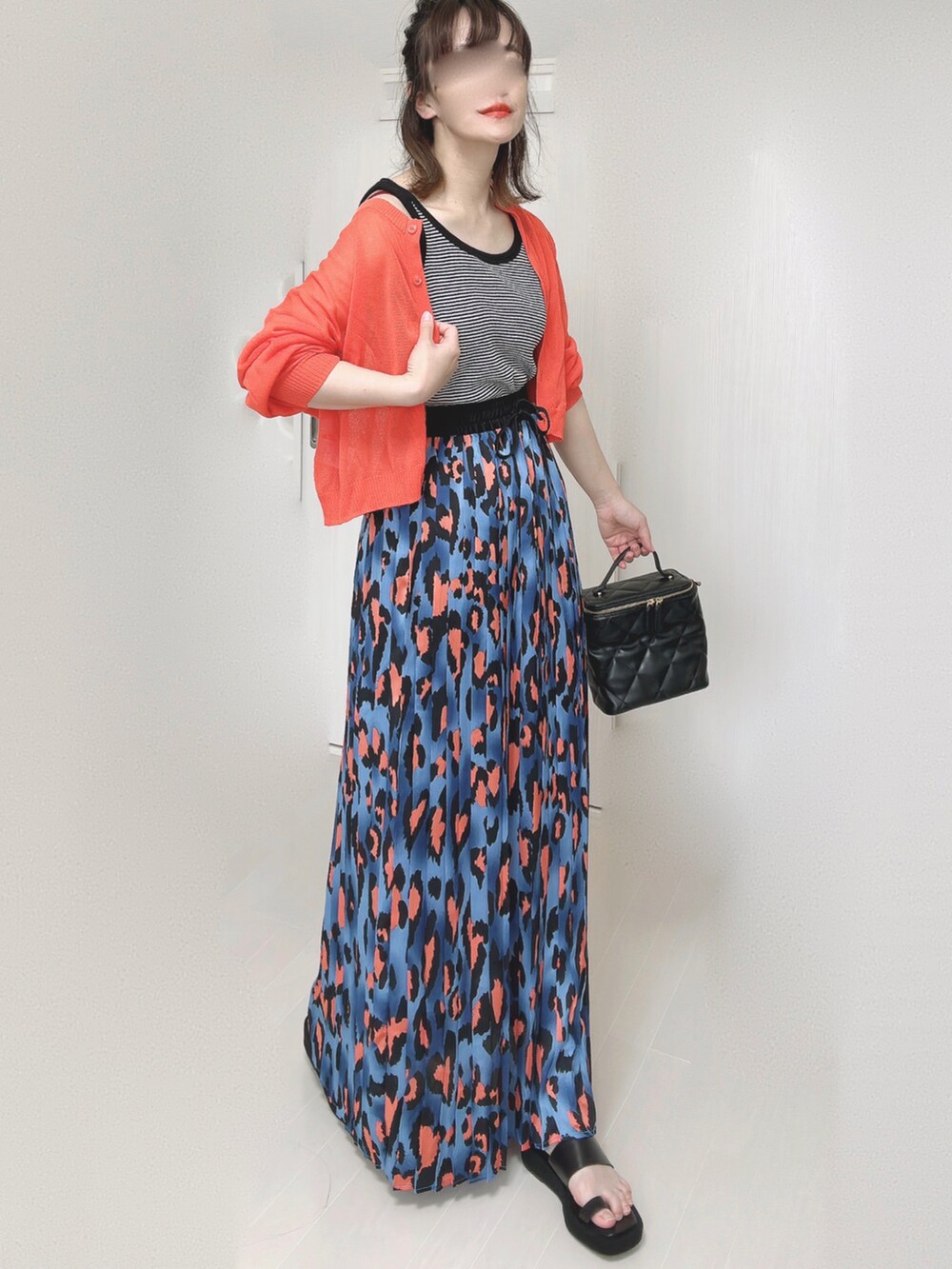 ブルー系のスカート、オレンジ系のカーディガン/ボレロ、ブラック系のタンクトップを着用したレディースの夏コーディネートの3枚目の写真