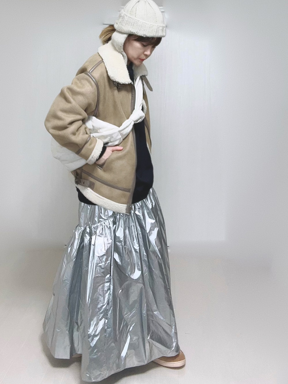 ベージュ系のムートンコート、ホワイト系のショルダーバッグ、シルバー系のスカートを着用したレディースの冬コーディネートの2枚目の写真