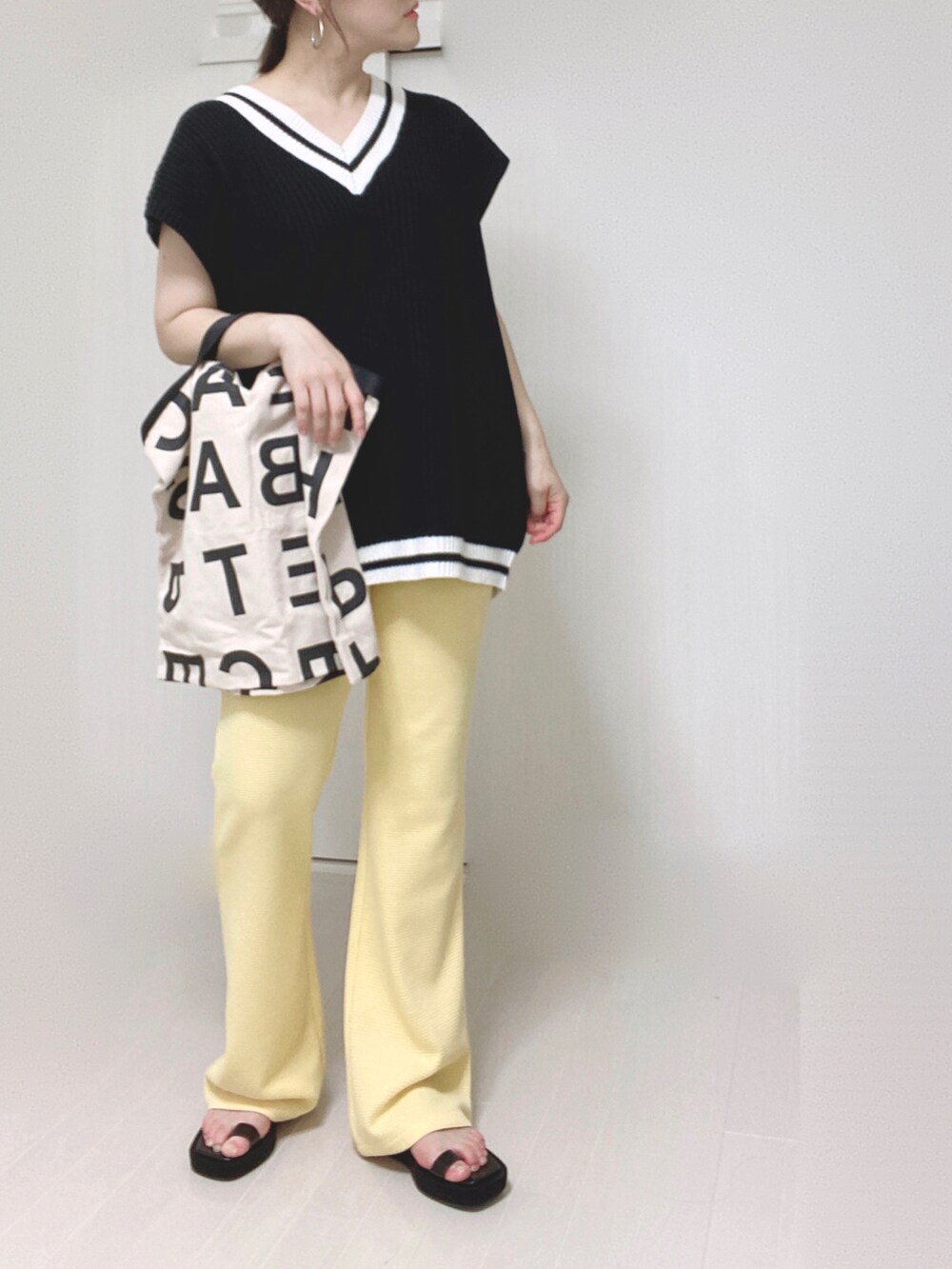 イエロー系のその他パンツ、ブラック系のベスト、ホワイト系のトートバッグを着用したレディースの夏コーディネートの5枚目の写真