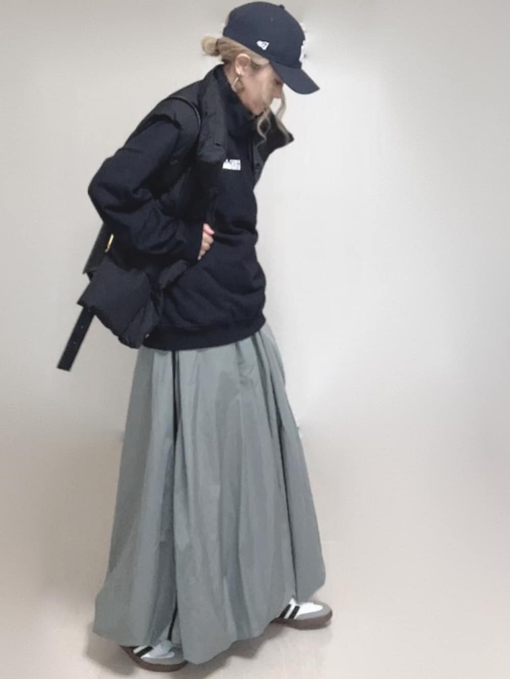 ブラック系のダウンベスト、ブラック系のスウェット、ブルー系のキャップを着用したレディースの秋コーディネートの5枚目の写真