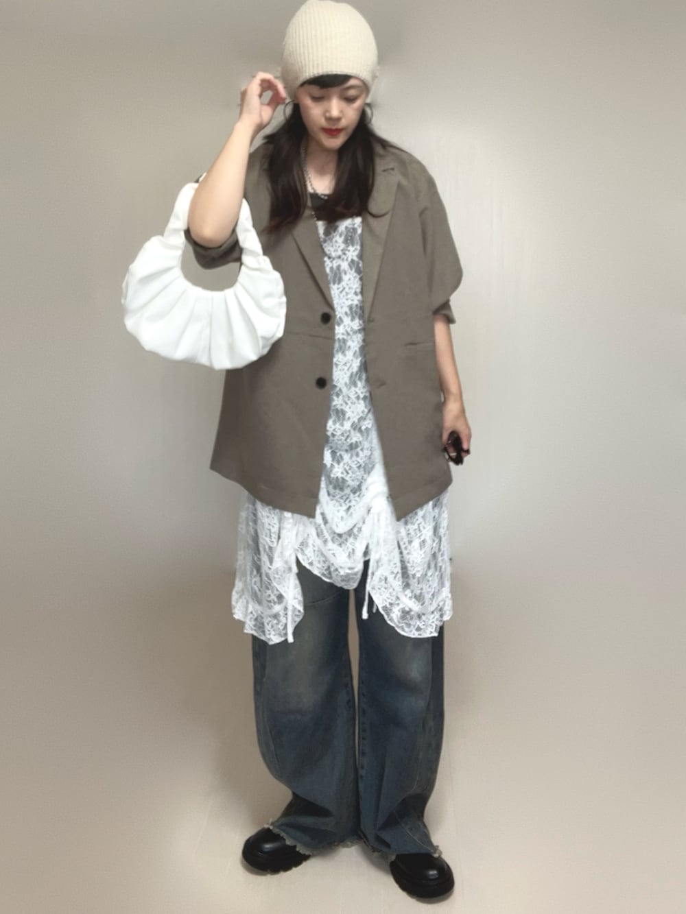 ベージュ系のテーラードジャケット、ホワイト系のチュニック、ブラック系のブーツを着用したレディースの夏コーディネートの3枚目の写真